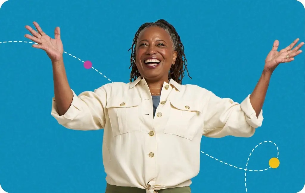 Smiling woman with braided hair raises her arms joyfully against a blue background with playful dotted lines and colorful circles. She wears a light button-up shirt and olive pants.